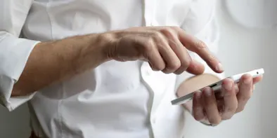 Niste flori mov pe o carte groasă si veche, langa o clepsidra mare in care curge nisipul